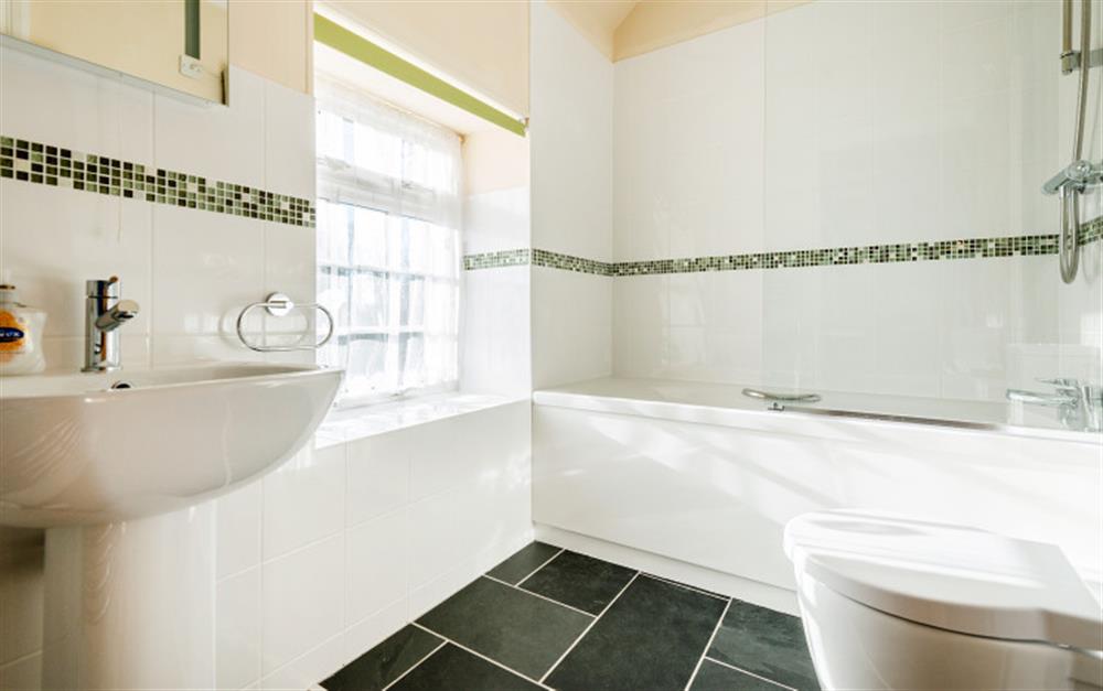 The family bathroom is modern and light with a shower fitted over the bath. at Rainbow Cottage in Porthallow