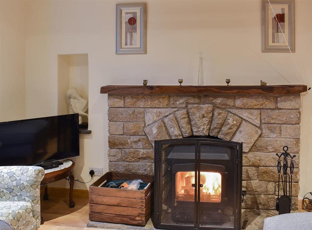 Living room with feature fireplace and wood burner at Ramshead Cottage in Tebay, near Kendal, Cumbria