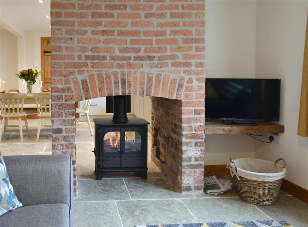 Characterful living area with wood burner in double sided fireplace at Cow Slip, 