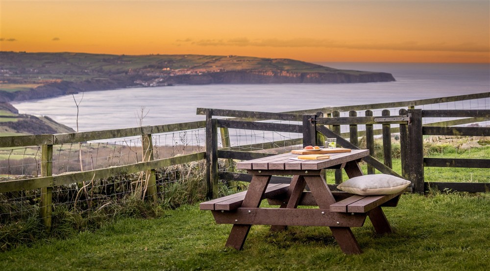 The garden with picnic table and views across the bay at Ravenscar Chapel Cottage in Scarborough, North Yorkshire