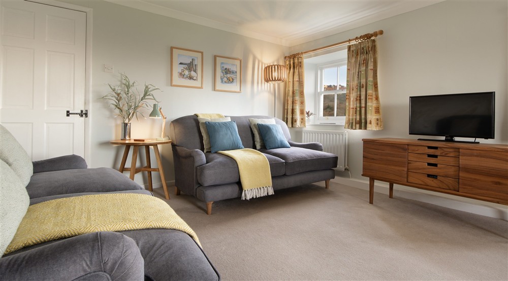 The sofas and television in the sitting and dining room at Ravenscar Chapel Cottage in Scarborough, North Yorkshire