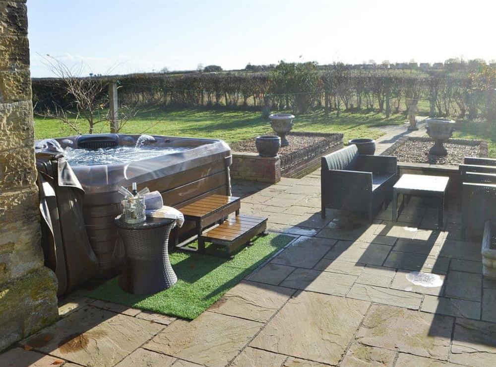 Paved outdoor area with bubbling hot tub at Red Hen Cottage in Acklington, Northumberland