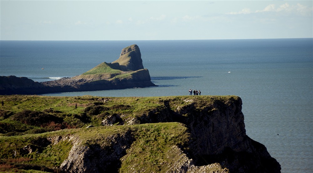 An aerial view of visitors on the cliffs looking towards Worms Head, South Wales at Rhossili Old Rectory in Rhossili, South Wales