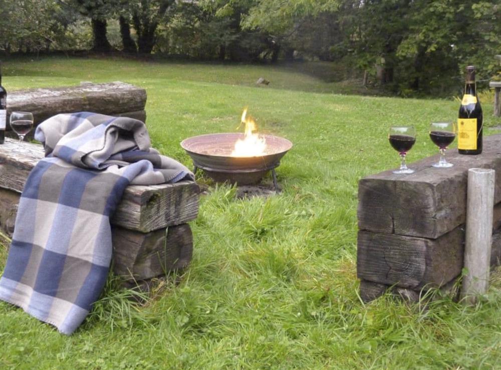 Fire-pit area with rustic seating within the gardens at Ringslade Barn in Highweek, near Newton Abbot, Devon
