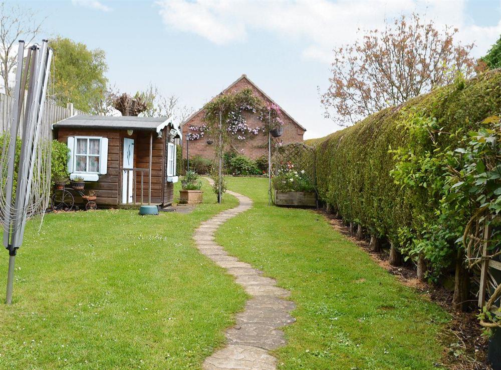 Lawned garden with playhouse at Ringstead Cottage in Ringstead, Norfolk