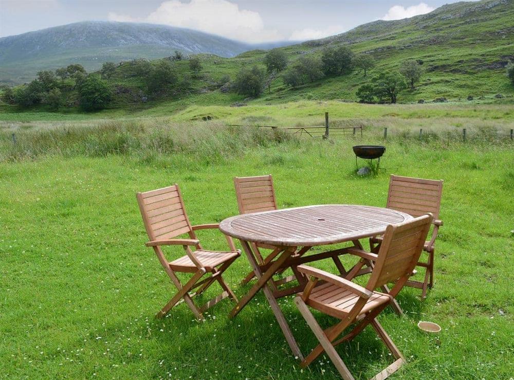 Lawned garden with table and chairs from which to take in the magnificent view at Riverside Cottage in Inchnadamph, near Lochinver, Sutherland