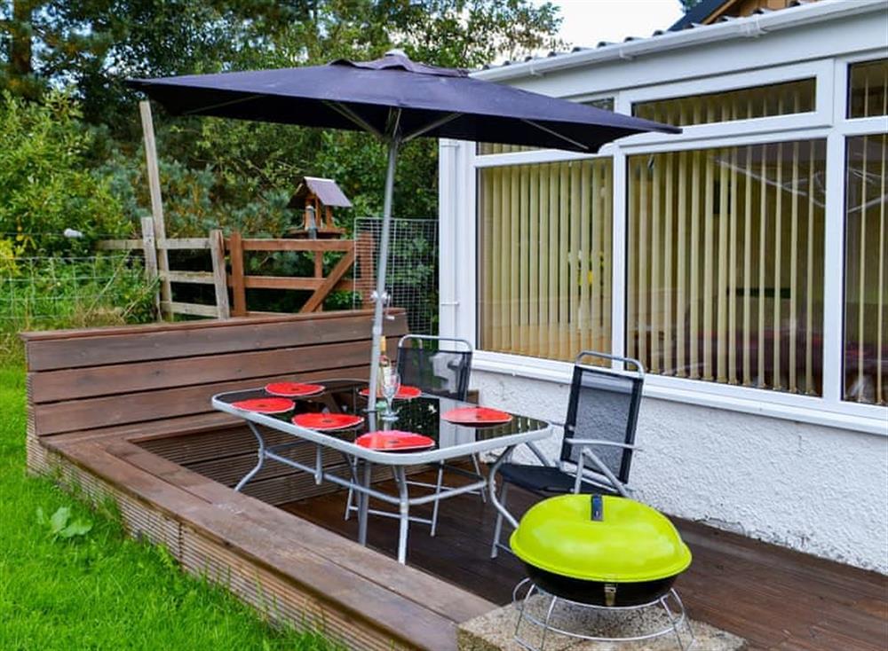 Enclosed lawned garden with sitting-out area and garden furniture at Roe Deer Cottage in Broallan, near Beauly, Inverness-Shire