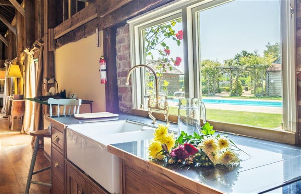 Kitchen with views out onto the swimming pool at Rose Barn, Stoke By Nayland