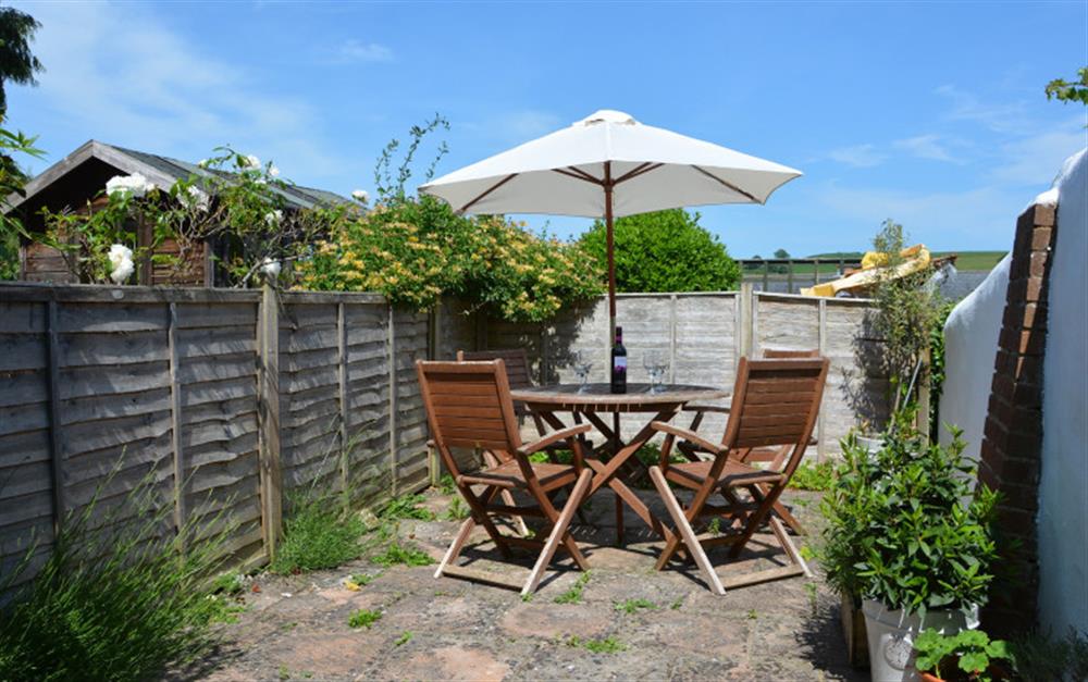 Private patio area with seating and a table at Rose Cottage Annexe in Colyton