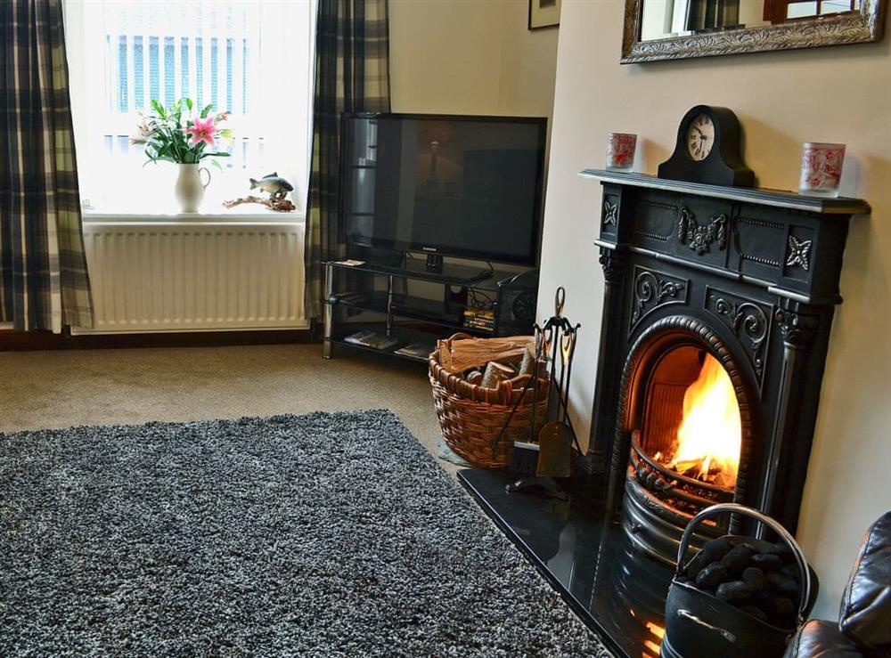 Warm and welcoming living room with open fire at Rose Cottage in Norham, near Berwick-upon-Tweed, Northumberland