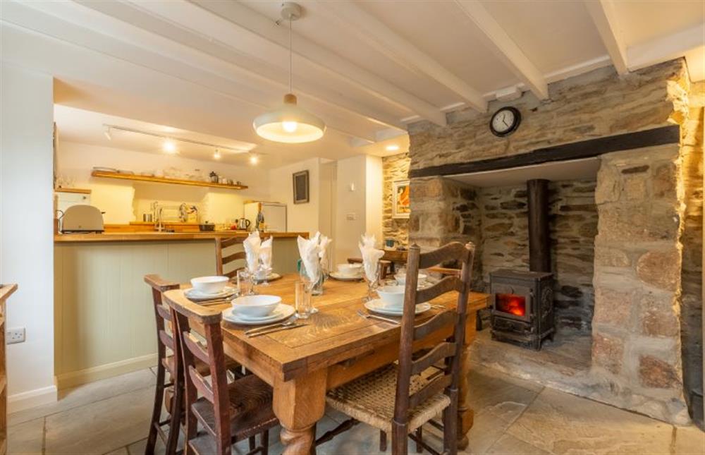 Dining area with table and a inglenook fireplace with wood burning stove at Rose in Vale Cottage, Mithian, St Agnes 