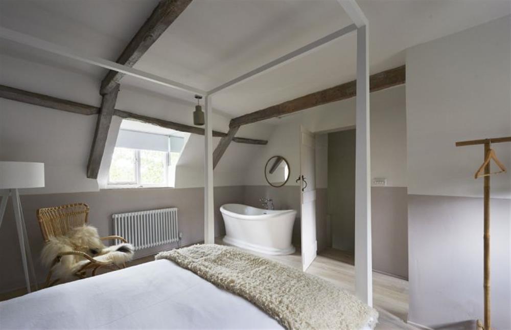 Master bedroom with four-poster king size bed and roll top bath at Salt, Sharrington near Melton Constable