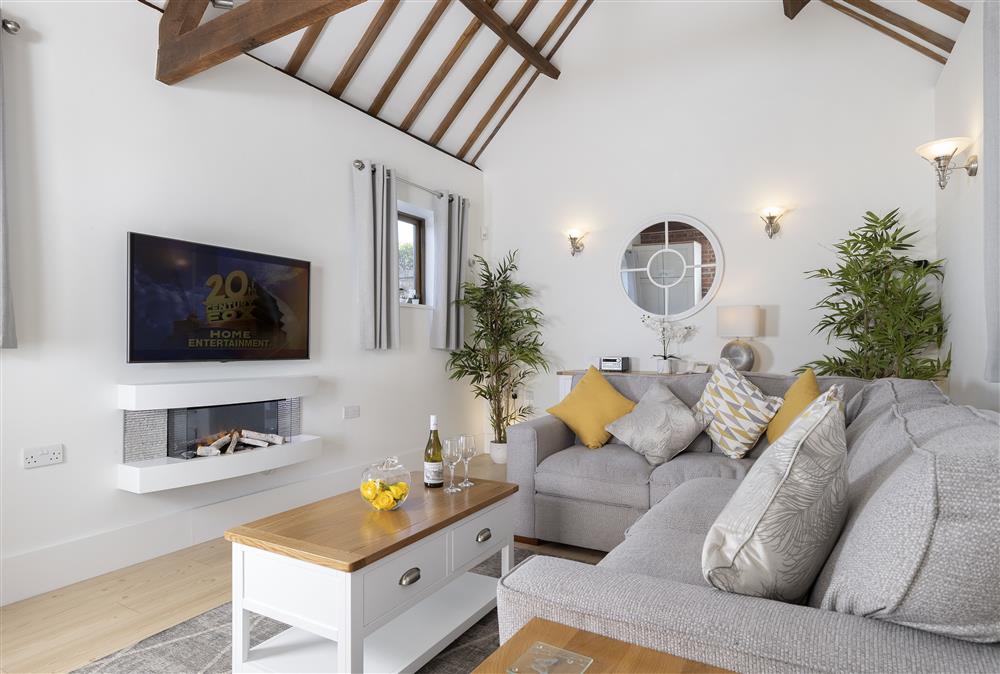 The sitting room with vaulted ceiling, electric fire and original exposed beams at Sandfields Barn, Luddington
