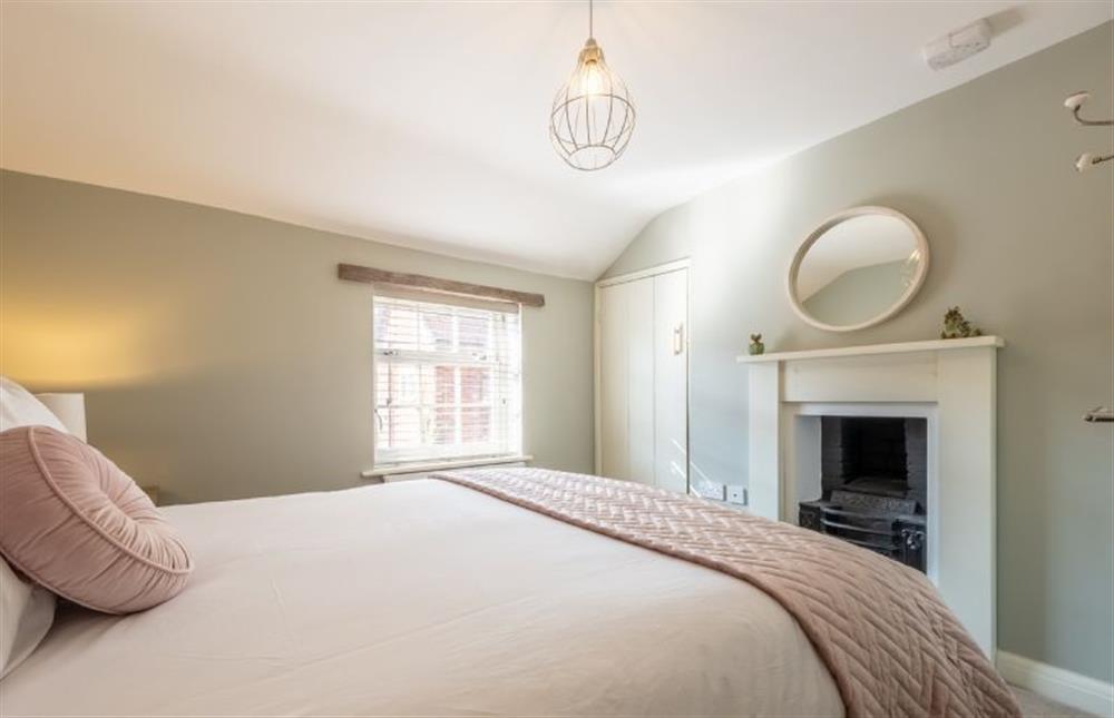 Sandpiperfts Cottage: Master bedroom with a double bed and a feature fireplace at Sandpipers Cottage, South Creake near Fakenham