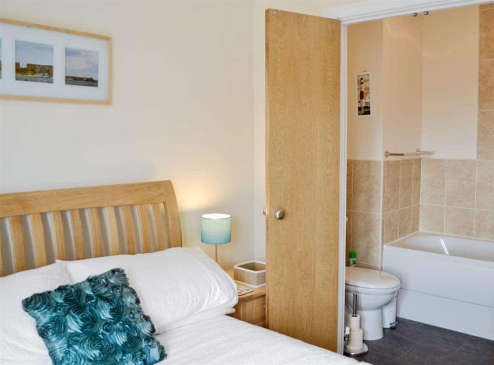 Double bed and en-suite with shower over bath and toilet at Sea Breeze in Beadnell, Northumberland