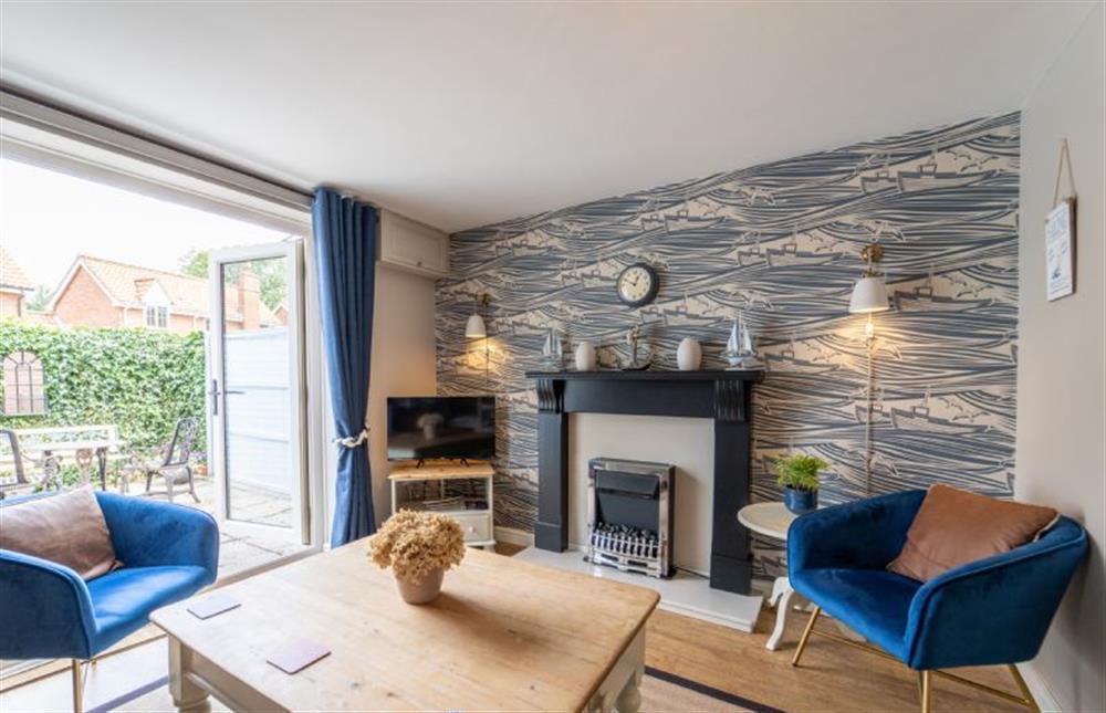 Feature wallpaper and an electric stove in the sitting room at Sea Holly Cottage, Snettisham near Kings Lynn