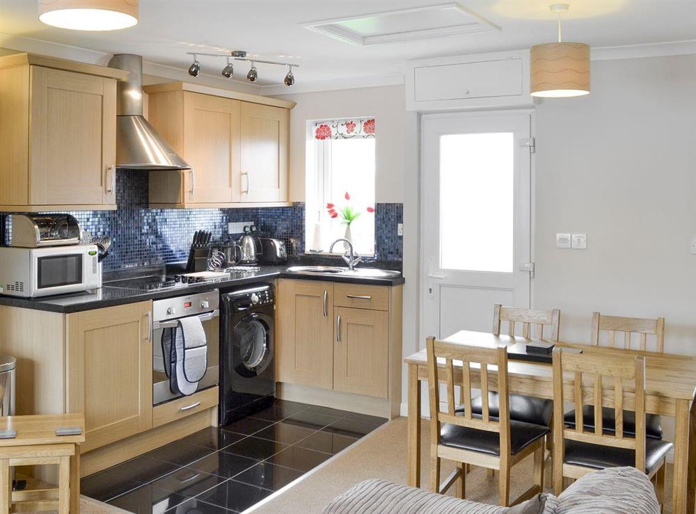 Well-equipped fitted kitchen and dining area within an open-plan room at Sea Thrift in Port Isaac, Cornwall
