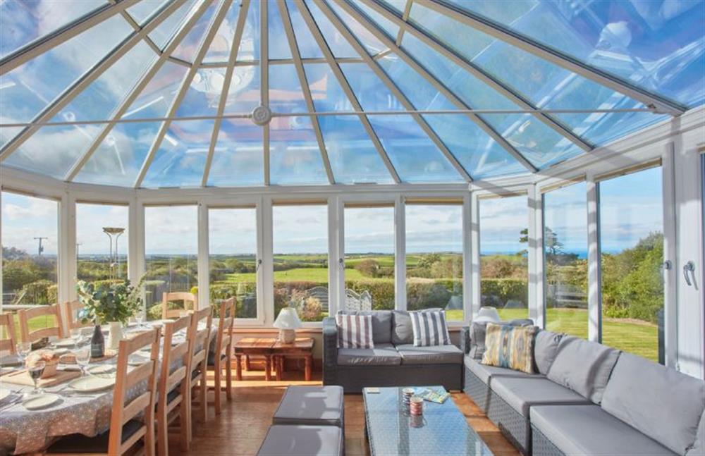 Ground floor: Spacious living area in the conservatory with dining area for ten guests. Views overlooking the garden and distant sea views