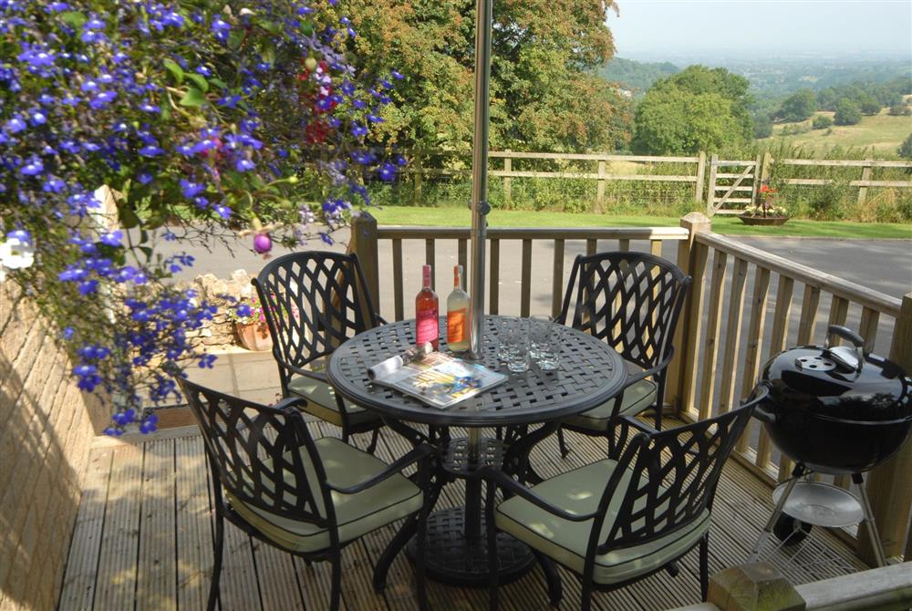 Elevated decking area with seating for four, parasol and a charcoal barbecue