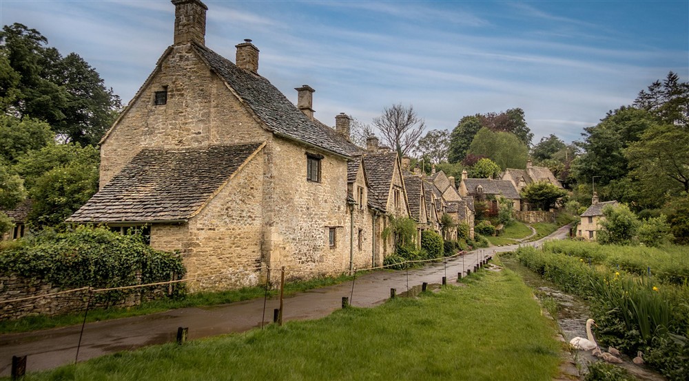Arlington Row and the water meadow, with a swan and signets in the water. Number 1 is at Sherborne West Lodge in Sherborne, Gloucestershire