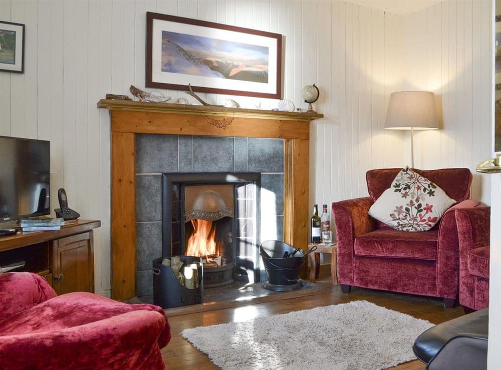 Welcoming living room with open fire at Shore Cottage in Arnisdale, near Glenelg, Ross-Shire