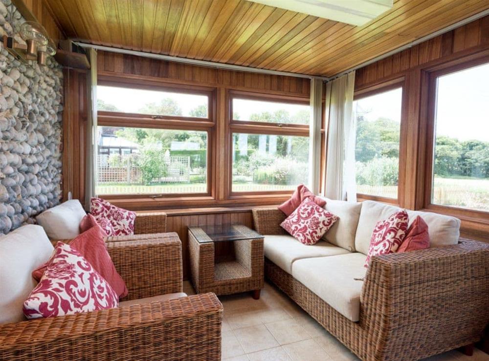 Comfortable seating with great views of the shared gardens from the conservatory at Sky Lark in Weybourne, Norfolk., Great Britain