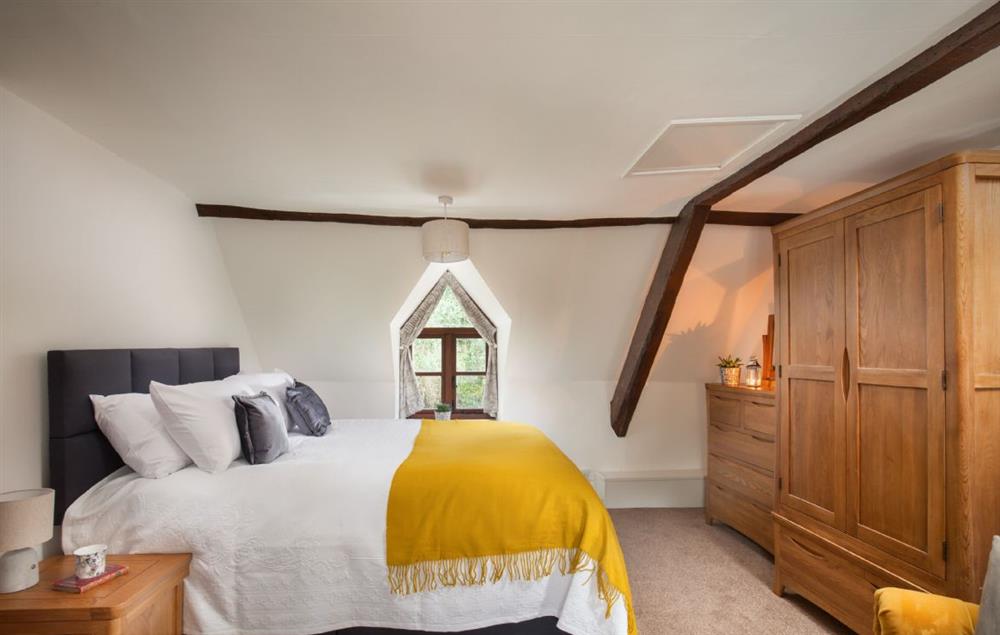 Master bedroom with traditional beams and feature window at Smithycroft, Combe St Nicholas