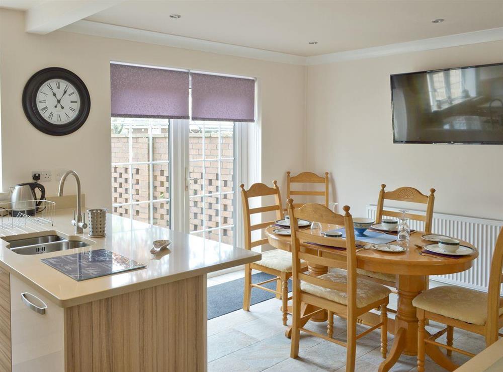 Stylish dining area of kitchen with French doors to rear courtyard at Smitten Cottage in Rhyl, Denbighshire