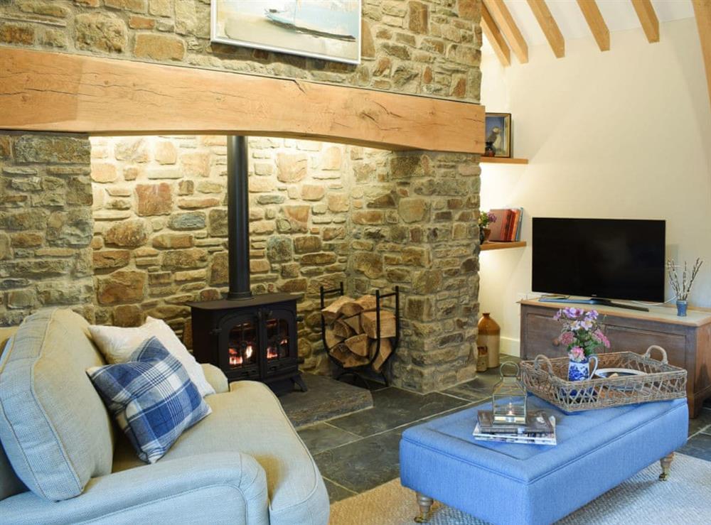 Imposing living room with feature stone wall and fireplace at Soar Cottage in Dihewyd, near Aberaeron, Ceredigion, Dyfed