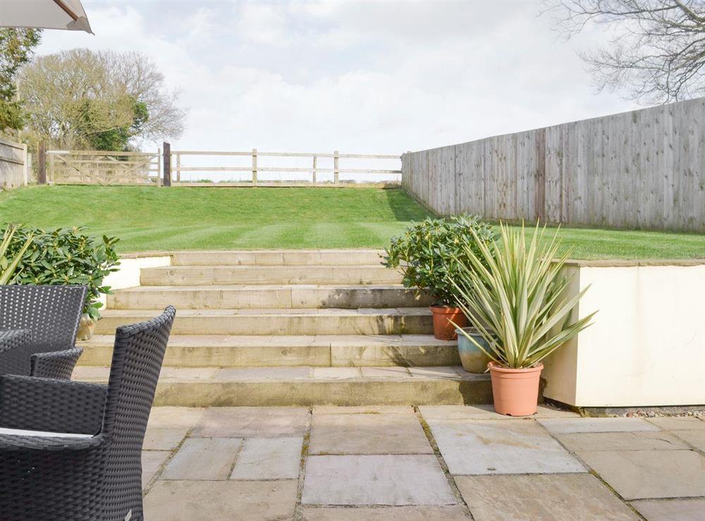 Steps from patio to enclosed lawned garden at Solitaire in South Creake, near Fakenham, Norfolk, England