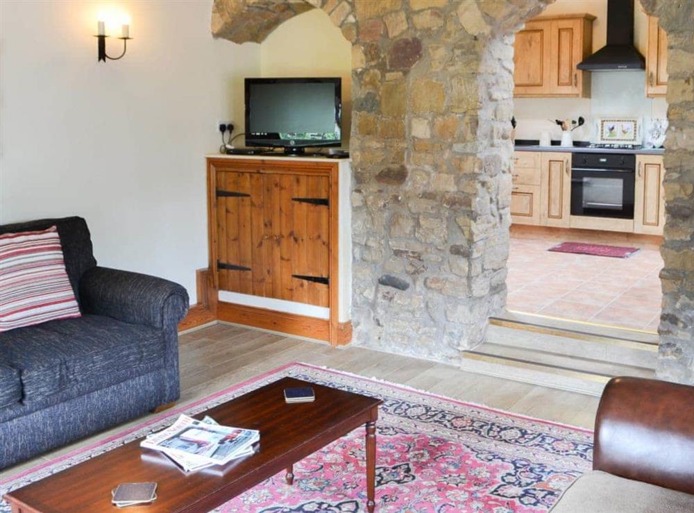 Living room with feature exposed stone wall at Cobweb Cottage, 