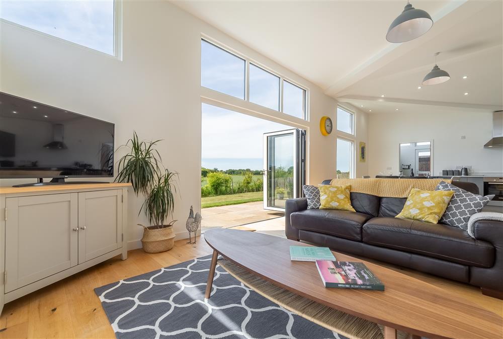 Bright modern sitting room with bi folding doors leading out to garden at South Barn, Ingham