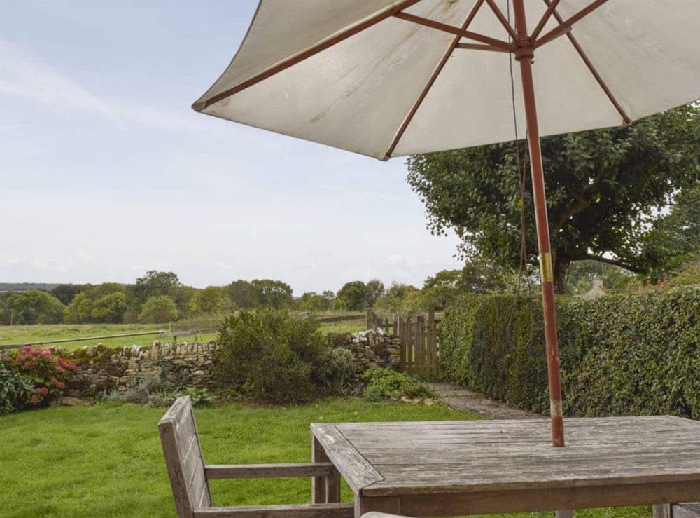 Outdoor furniture on the patio overlooks the enclosed garden at South View Cottage in Dean, near Chadlington, Oxfordshire