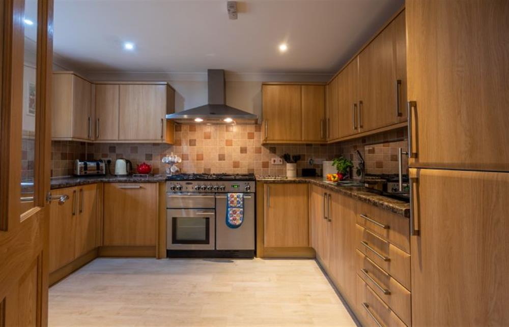 Well-equipped kitchen with an electric range cooker and gas hob, fridge/ freezer, microwave, dishwasher, and washing machine
