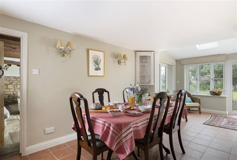 Ground floor: Dining room with seating for six guests leading into the garden room at Southcroft Cottage, Bredons Norton