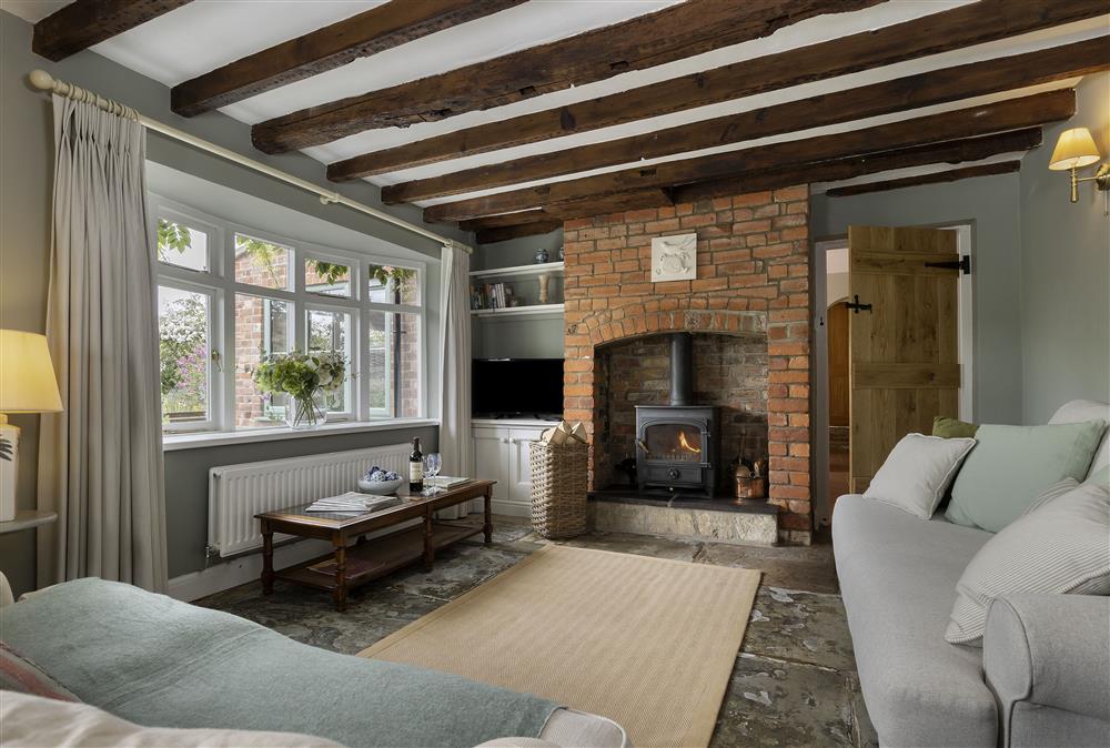 Ground floor: Sitting room with exposed beams and cosy wood burning stove at Southcroft Cottage, Bredons Norton