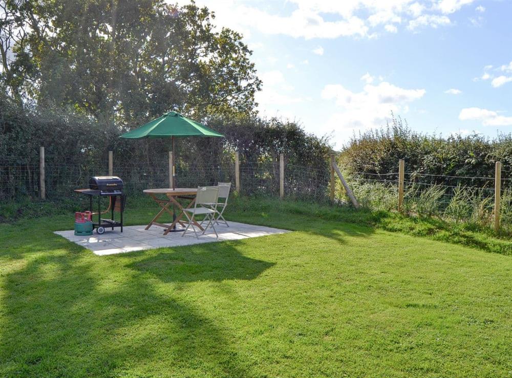 Enclosed lawned garden with outdoor seating and BBQ area at Southview in Porchfield, near Newport, Isle of Wight