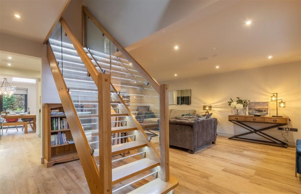 Open-plan layout with wood and glass balustrade staircase featuring illuminated steps