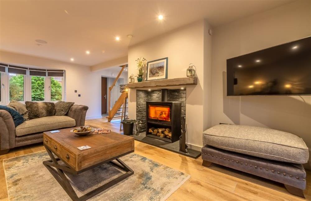 Open-plan sitting room with wood burning stove and wall mounted Smart TV at Spindrift, Old Hunstanton