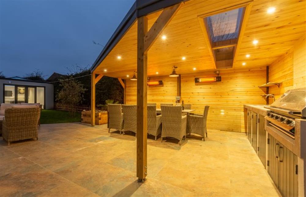 The heated, outdoor kitchen and dining area set on one side of the garden, and on the opposite side sits the timber-framed games room 