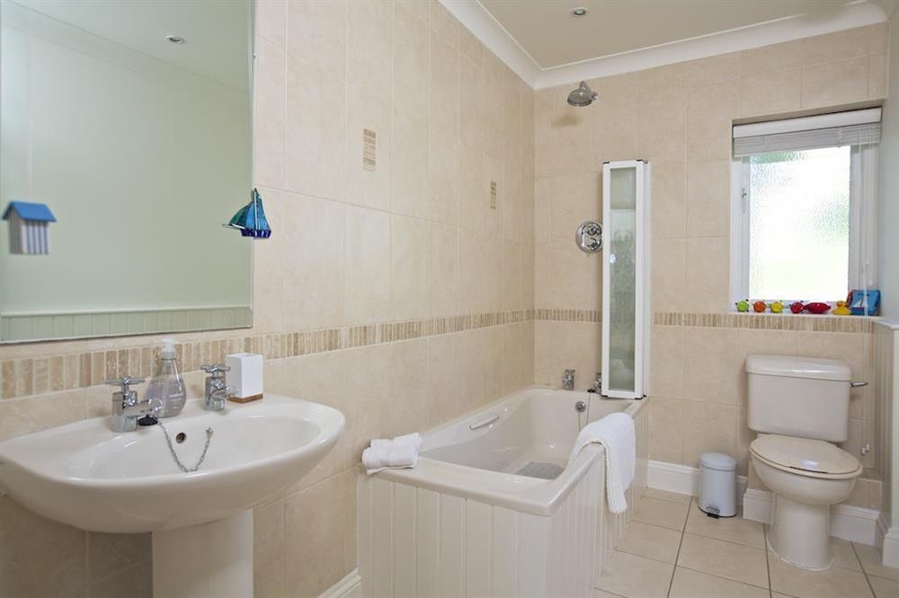 Family bathroom with shower over bath and large mirror behind the sink at Spindrift in , Thurlestone
