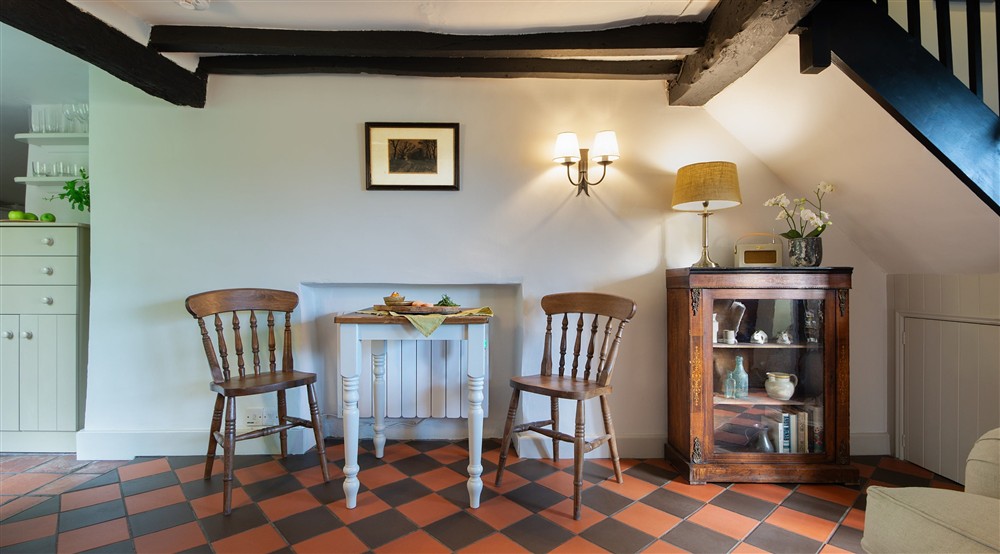 The dining area with table and chairs for two in the open-plan sitting and dining room at Spring Cottage in Broadway, Gloucestershire