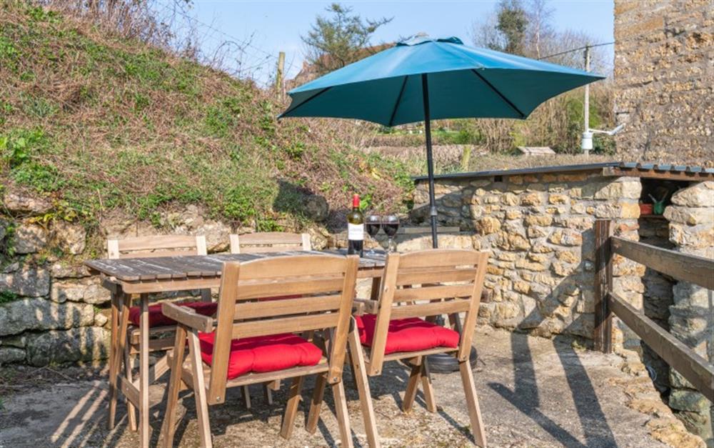 Seating area with table, chairs and parasol at Spring Cottage in Powerstock