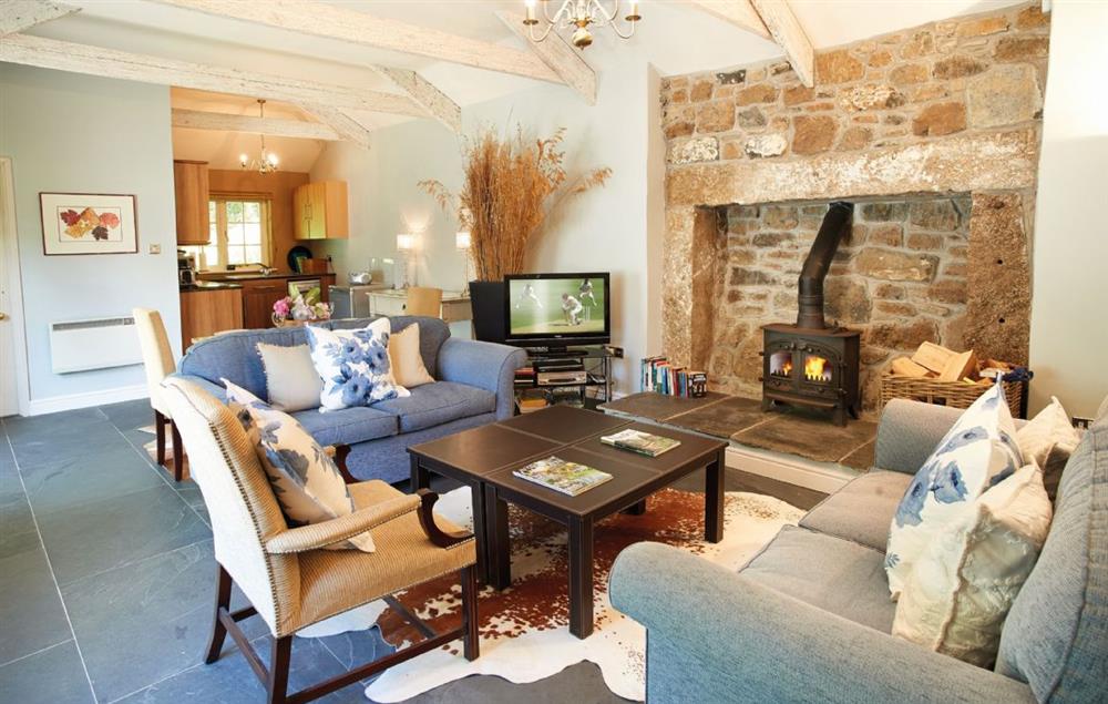 Open plan sitting room with wood burning stove and dining area at Spring Water Barn, Helston