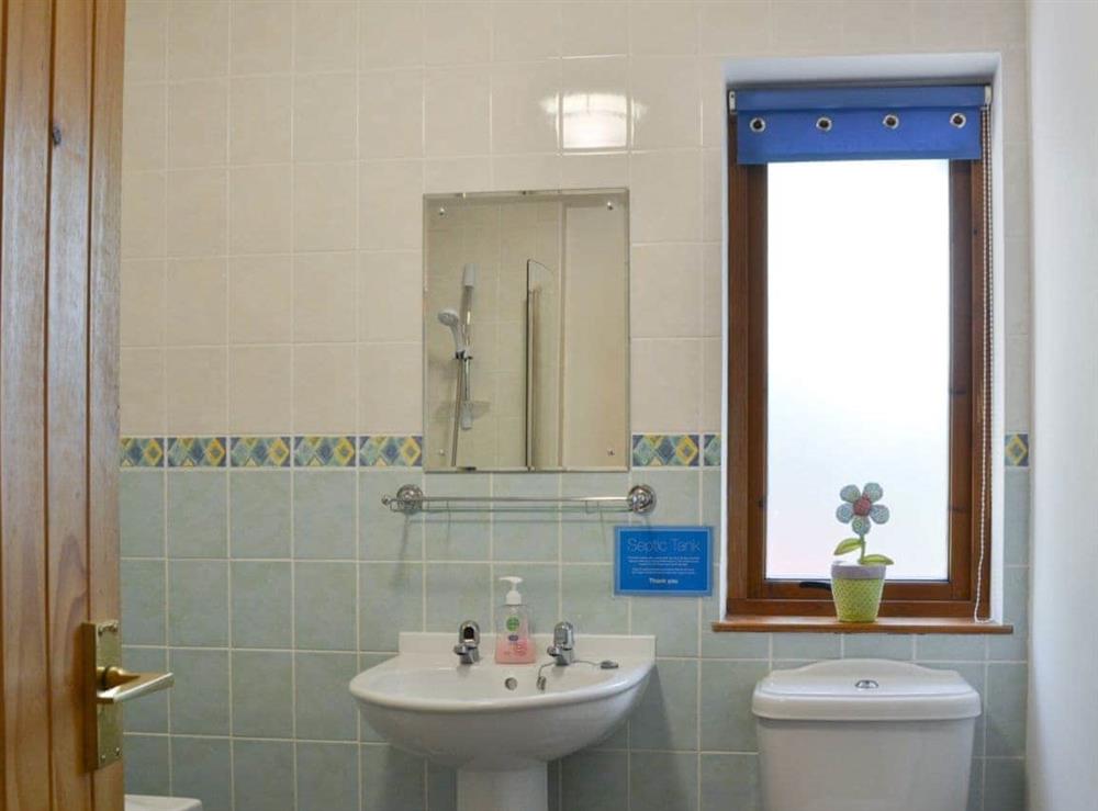 Half-tiled bathroom with shower over the bath at Squirrel Cottage in North Kessock, Inverness-Shire
