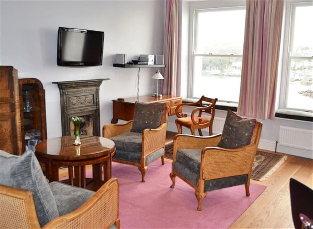 main living area with oak flooring is open plan and comfortably furnished with retro 1930’s style furniture at St Catherines Court No 4 in Fowey, Cornwall