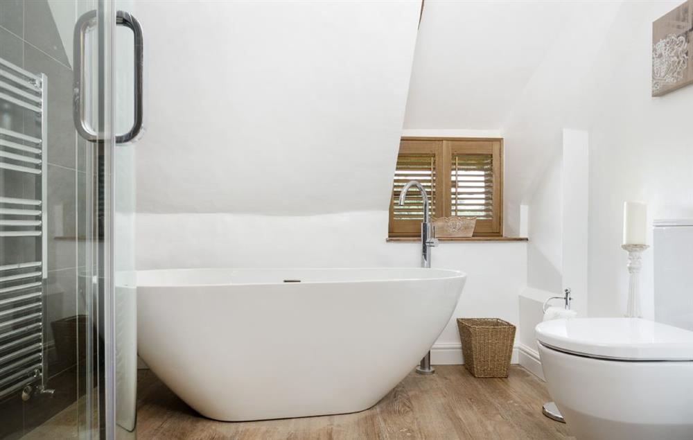 First floor: Family bathroom with deep bath  tub and walk in shower at St Michaels Cottage, Broadway