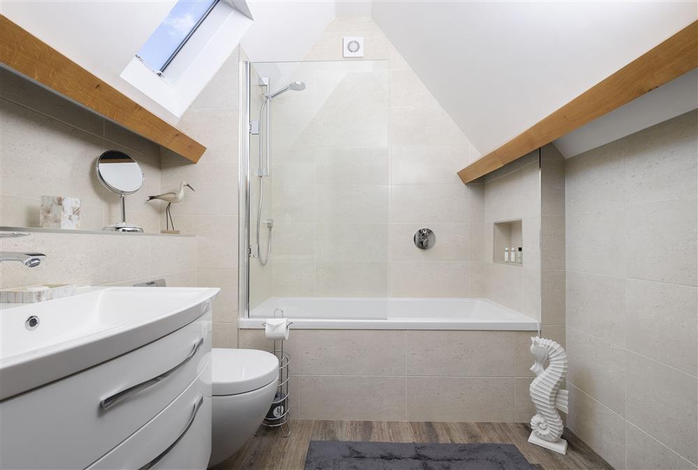 First floor: En-suite bathroom to bedroom one with bath and overhead shower  at Stable Barn, Little Rissington