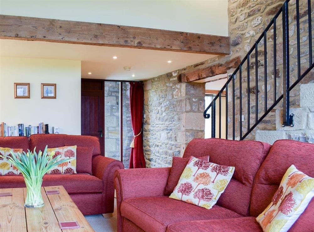 Living room with exposed stone walls and open staircase to first floor at Stable Cottage in Airton, Nr Skipton., North Yorkshire