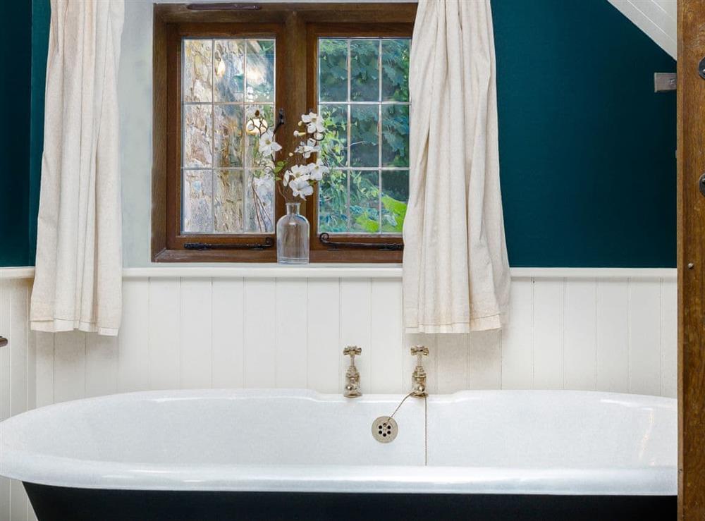 Free-standing roll-top bath within bathroom at Stable Cottage in Uley, near Dursley, Gloucestershire